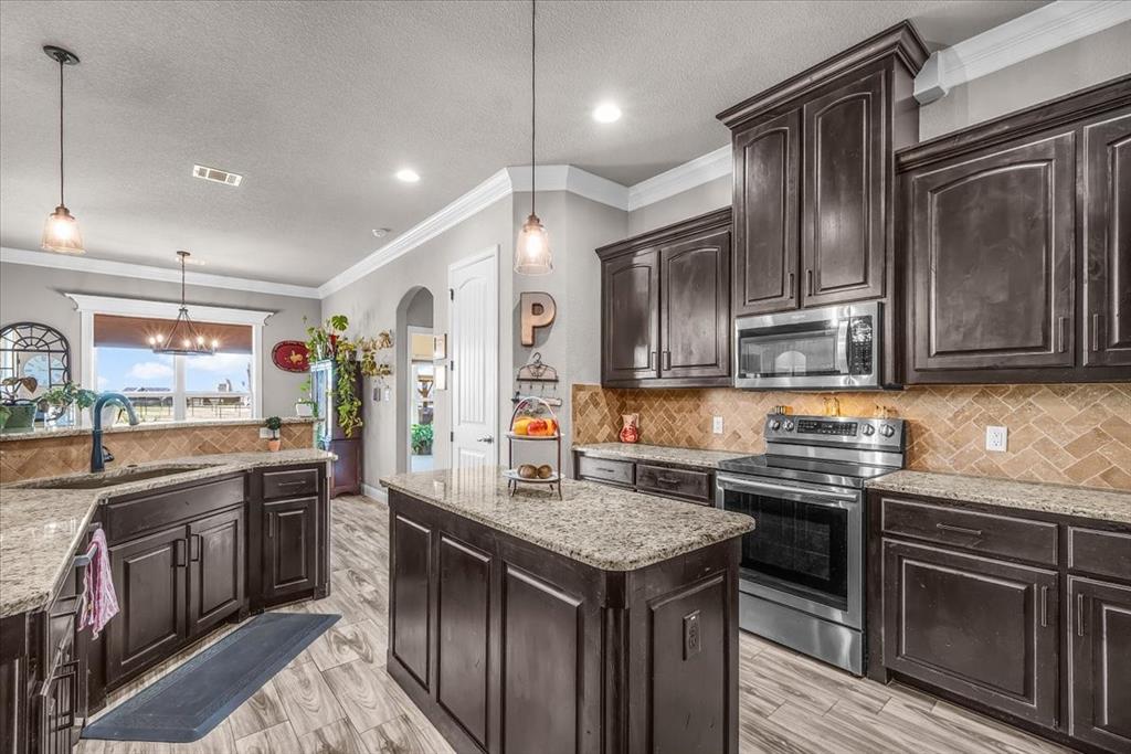 139 Stanford Lane Springtown, TX 76082 - Photo 12 of 36 Kitchen featuring dark wood finish cabinetry, crown molding, and stainless-steel appliances