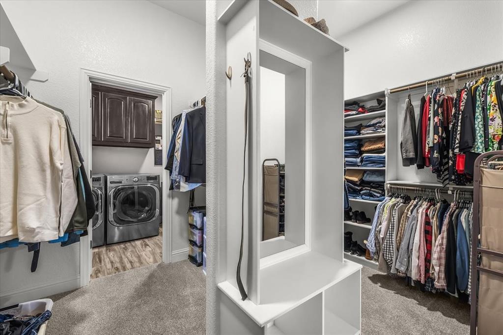 139 Stanford Lane Springtown, TX 76082 - Photo 19 of 36 Spacious walk-in closet with built-in shelving and a central dressing area with a mirror. The layout connects directly to the utility room.