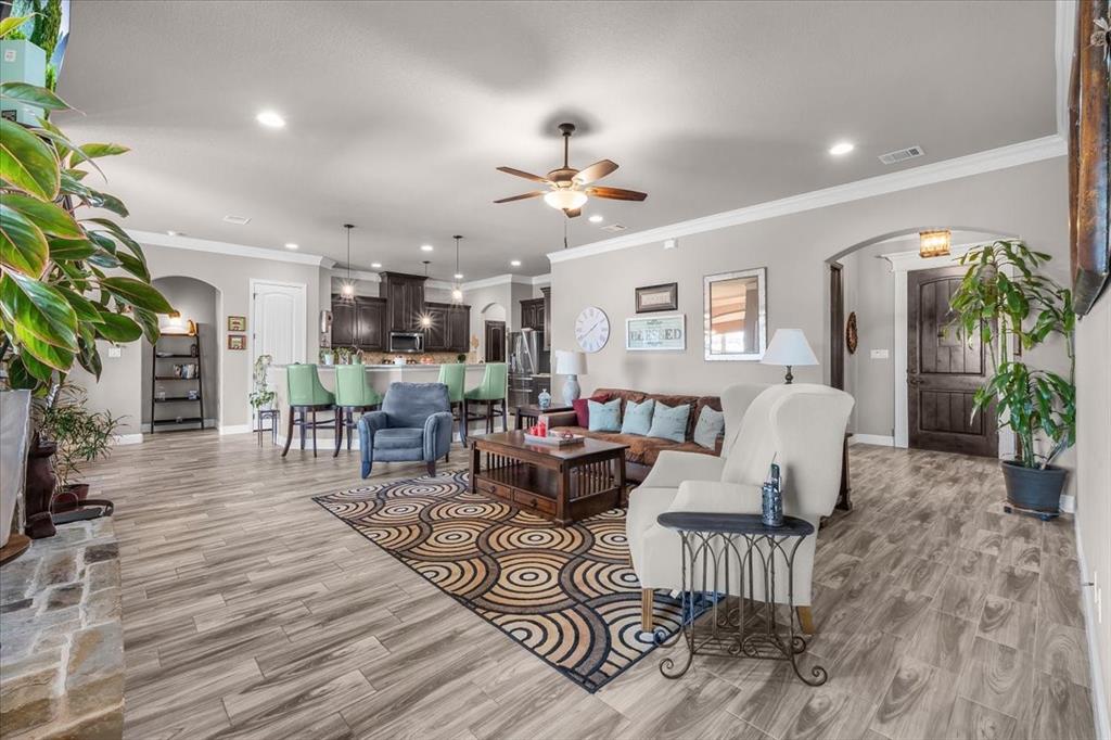 139 Stanford Lane Springtown, TX 76082 - Photo 10 of 36 Living area featuring ceiling fan, wood tiled floors, arched walkways, plenty of natural light, and crown molding
