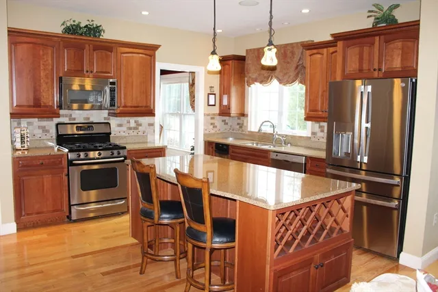 a kitchen with stainless steel appliances granite countertop a refrigerator a stove and a sink with wooden floor