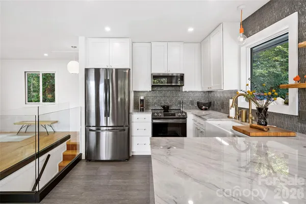a kitchen with stainless steel appliances granite countertop a stove and a white cabinets