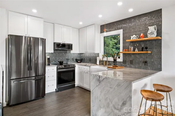 a kitchen with stainless steel appliances granite countertop a refrigerator a stove a sink and a microwave