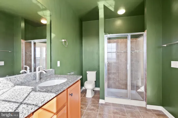 a bathroom with a granite countertop sink a toilet and shower
