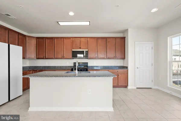 a kitchen with stainless steel appliances granite countertop a sink a stove a refrigerator a center island and cabinets