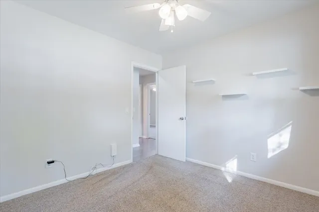 an empty room with a chandelier fan and windows