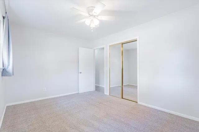 an empty room with a ceiling fan and a window