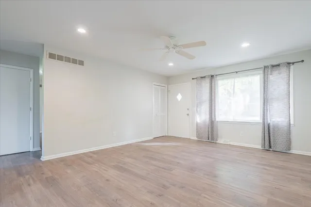 a view of an empty room with wooden floor and a window