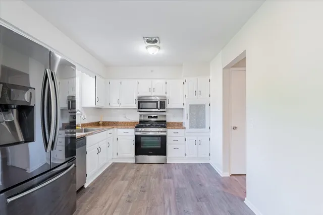 a kitchen with granite countertop a refrigerator stove top oven and sink
