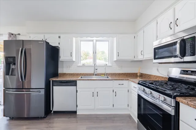 a kitchen with white cabinets stainless steel appliances and a window