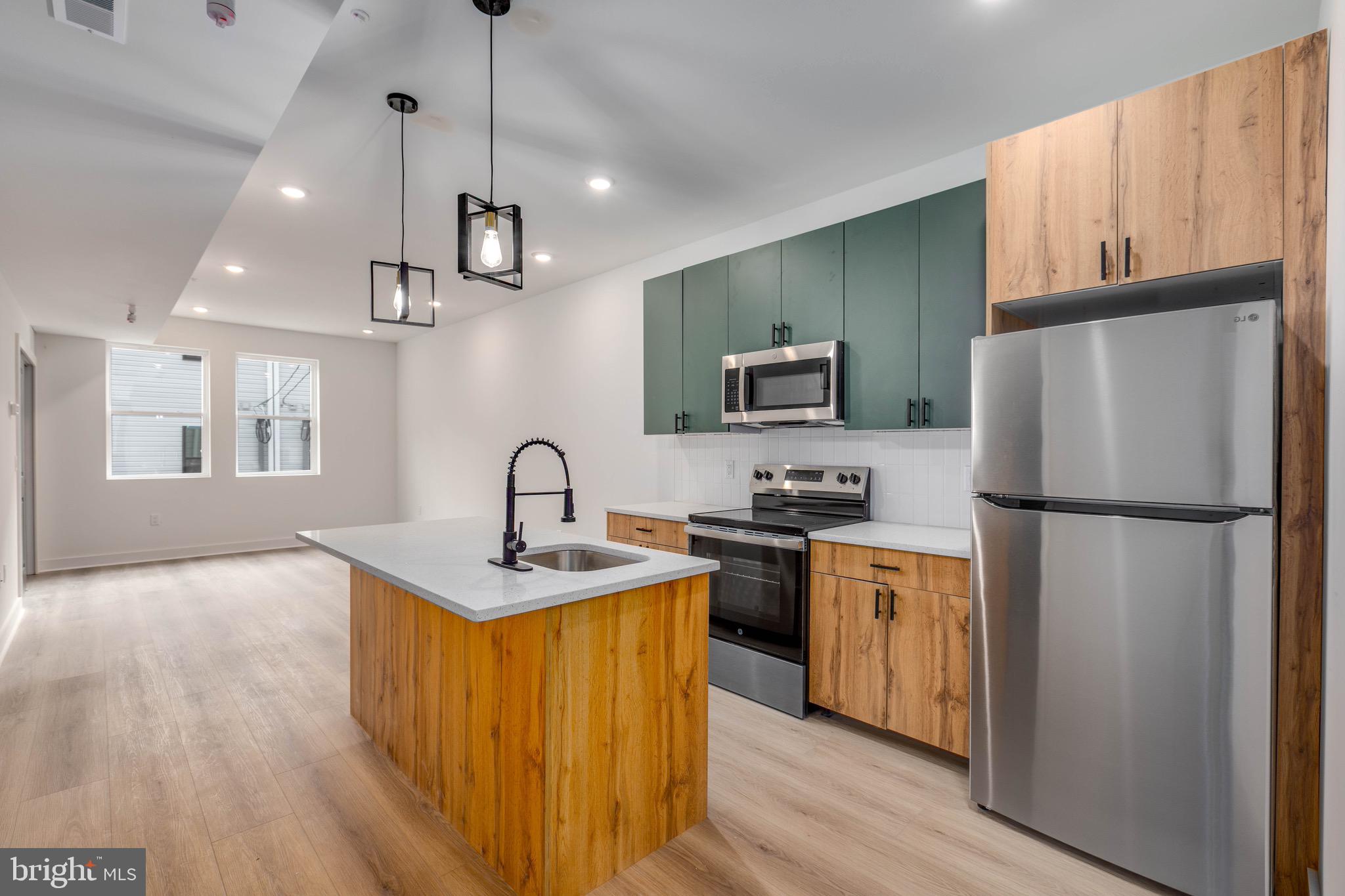 1224 West Silver Street, Unit 2 Philadelphia, PA 19133 - Photo 1 of 11 a kitchen with stainless steel appliances granite countertop a refrigerator a stove top oven a sink dishwasher and a refrigerator with wooden floor