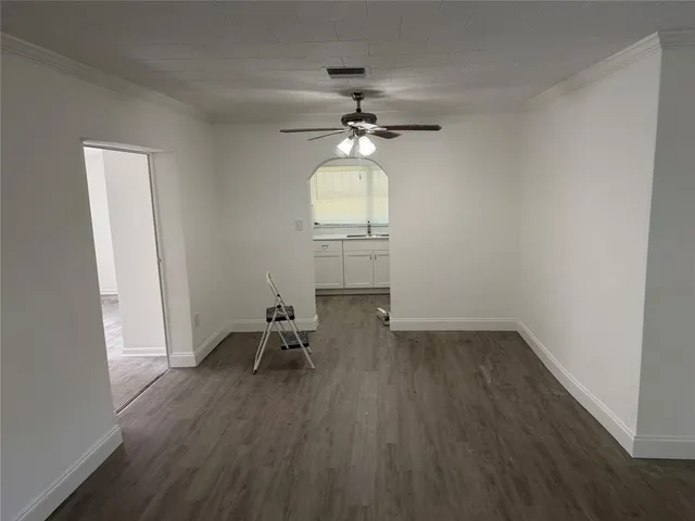 an empty room with wooden floor table and chairs