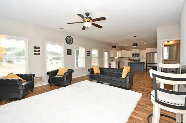 a living room with furniture kitchen view and a large window
