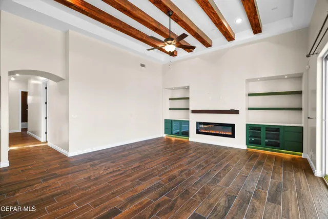 an empty room with wooden floor fireplace and windows