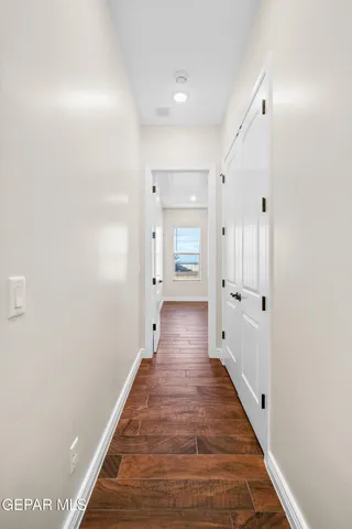 a view of an empty room with wooden floor and a ceiling fan