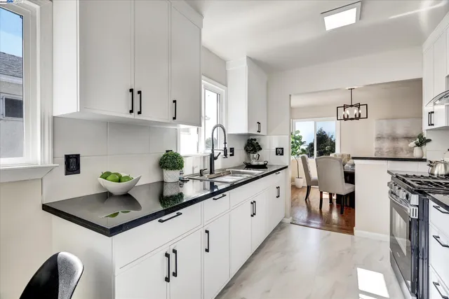 a kitchen with stainless steel appliances granite countertop a stove a sink dishwasher and white cabinets with wooden floor