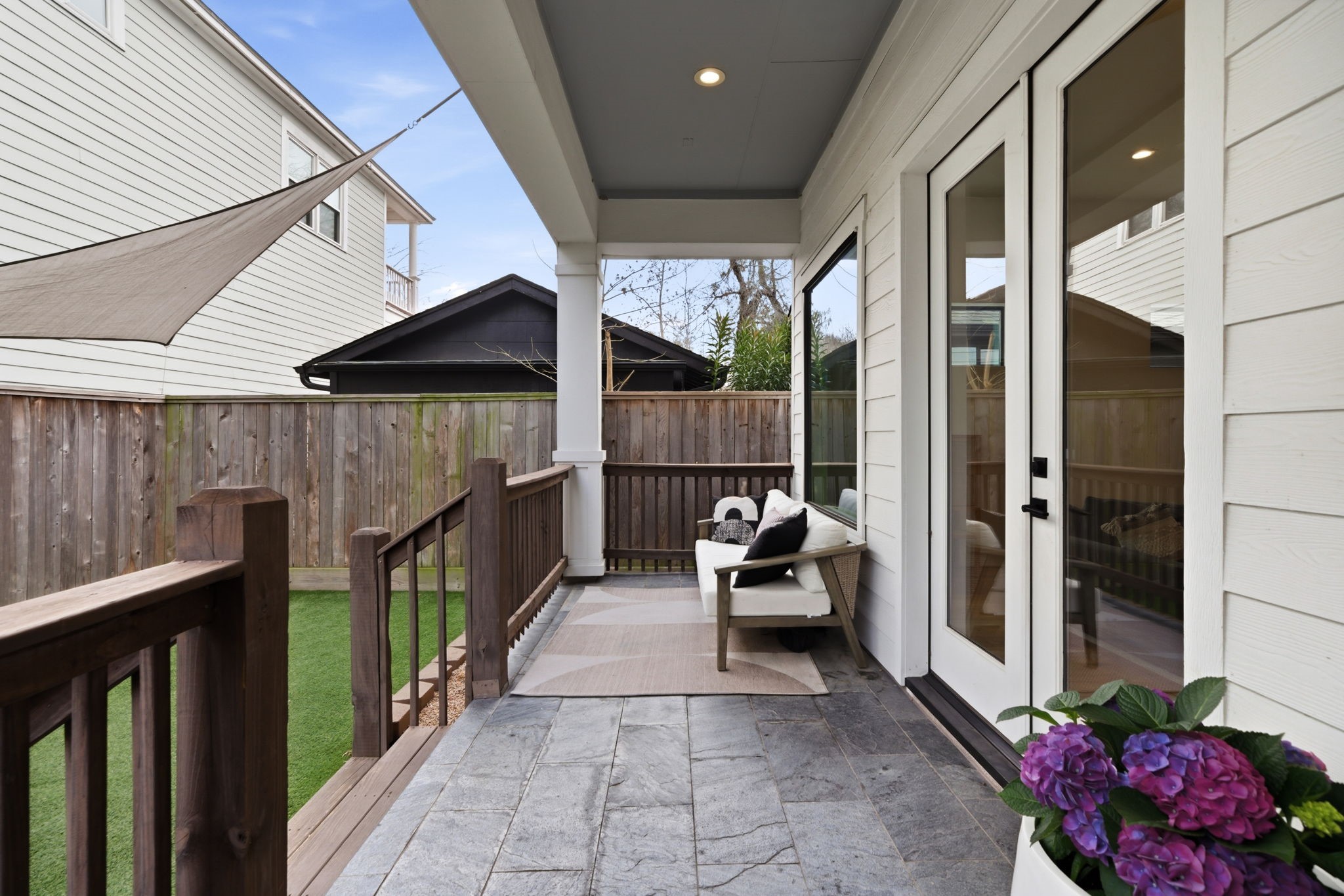 504 Oxford Street Houston, TX 77007 - Photo 14 of 47 The covered patio extends the living space outdoors with slate-style flooring and a ceiling fan for added comfort. French doors create an easy indoor-outdoor flow, making it ideal for casual gatherings or quiet evenings outside. The elevated deck overlooks the yard while offering privacy.