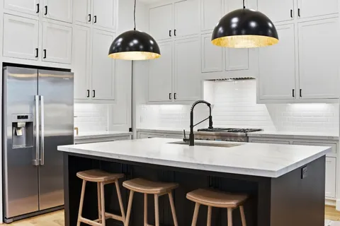 a kitchen with a stove a sink a counter top space and living room view