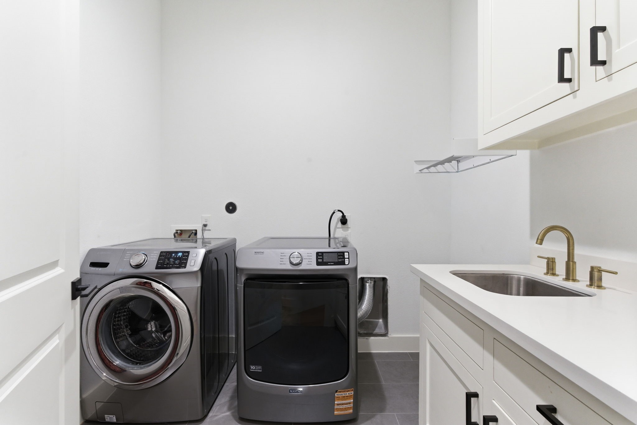 504 Oxford Street Houston, TX 77007 - Photo 25 of 47 The laundry room is thoughtfully designed with built-in cabinetry, a utility sink, and generous counter space. Clean finishes and matte black hardware tie into the rest of the home’s aesthetic. It’s a practical space that makes daily tasks more convenient.