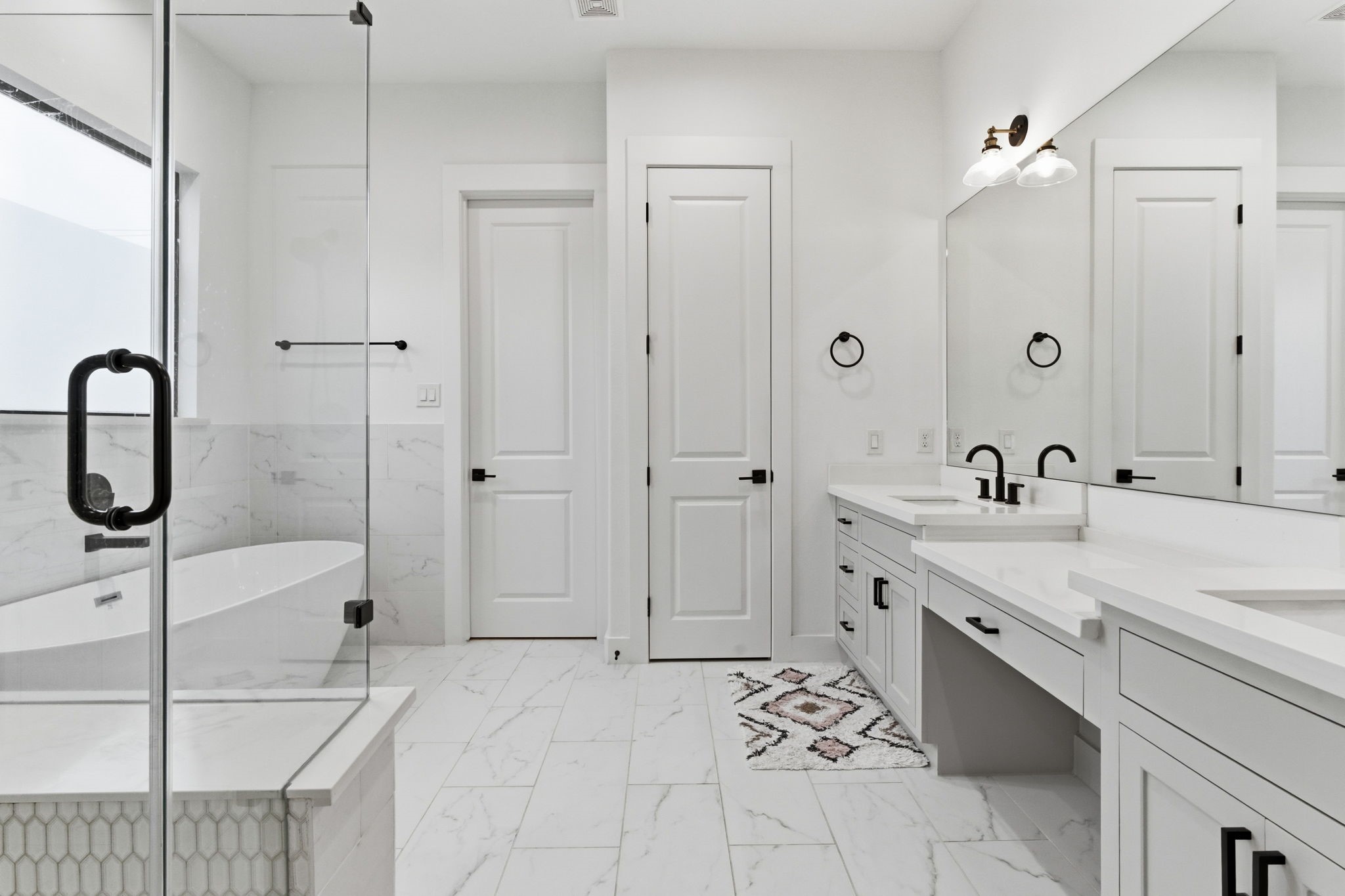 504 Oxford Street Houston, TX 77007 - Photo 28 of 47 The primary bath offers dual vanities with expansive counter space and ample storage. Crisp white cabinetry, matte black fixtures, and large-format tile create a clean, modern look. The layout feels both functional and elevated.