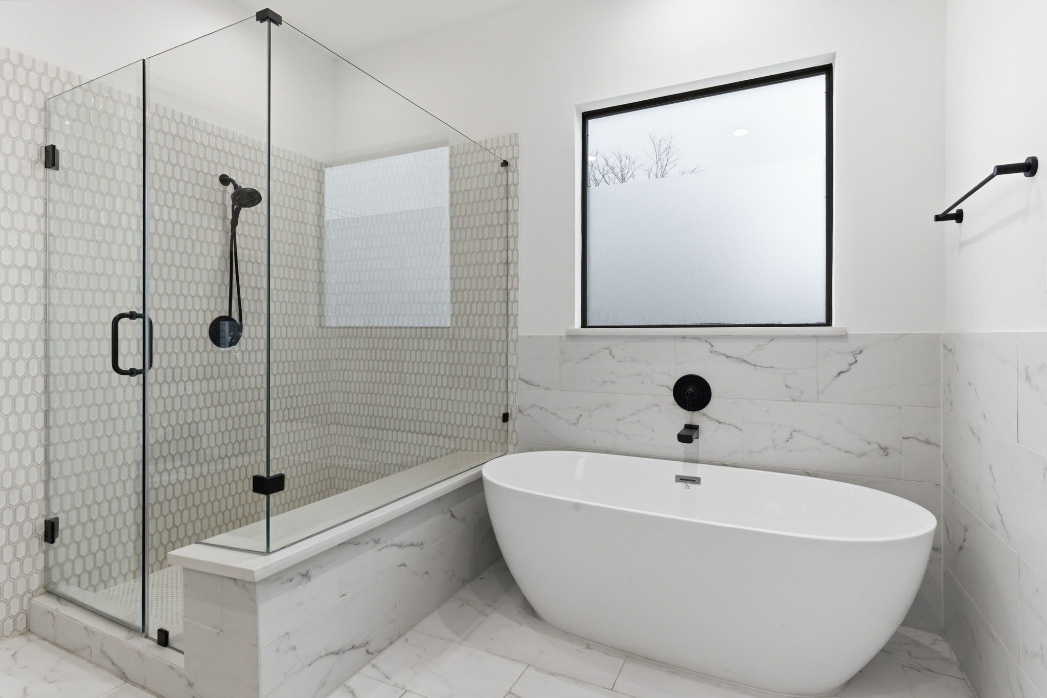 504 Oxford Street Houston, TX 77007 - Photo 29 of 47 A freestanding soaking tub and glass-enclosed shower create a spa-like setting. Marble-look tile and sleek black fixtures add contrast and sophistication. The frosted window allows natural light while maintaining privacy.