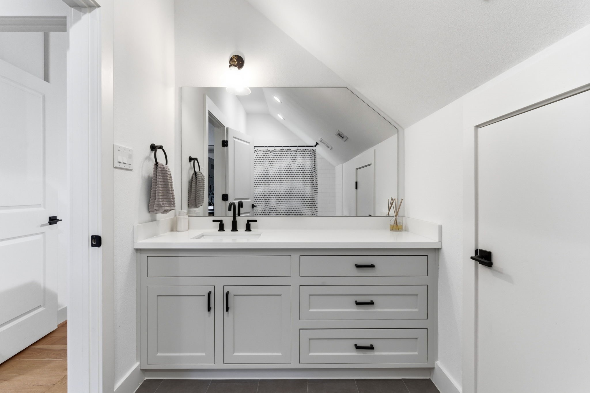 504 Oxford Street Houston, TX 77007 - Photo 41 of 47 This upstairs en suite bathroom features a wide vanity with generous drawer storage and quartz counters. Matte black fixtures and a full-width mirror keep the look clean and cohesive. The layout maximizes function while maintaining a modern feel.