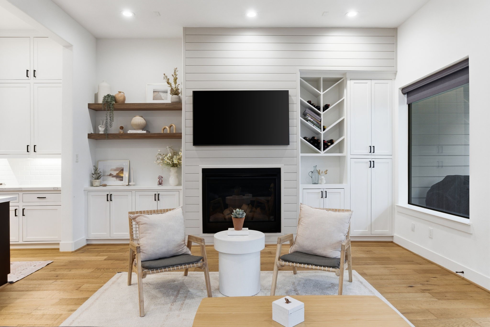 504 Oxford Street Houston, TX 77007 - Photo 9 of 47 A stunning shiplap fireplace wall anchors the living room with a mounted TV and sleek modern lines. Built-in cabinetry and open shelving provide stylish storage, including a dedicated wine nook for entertaining. Wide-plank wood floors and oversized windows keep the space bright, airy, and inviting.