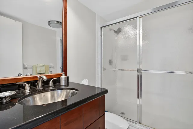 a bathroom with a granite countertop sink mirror and shower