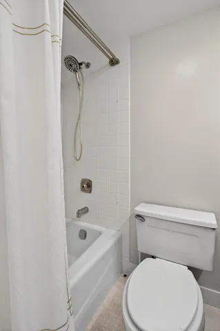 a white toilet sitting next to a bath tub