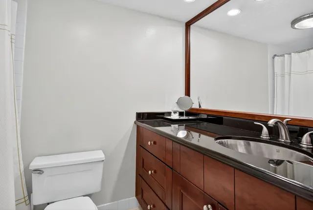 a bathroom with a granite countertop sink a toilet and a mirror