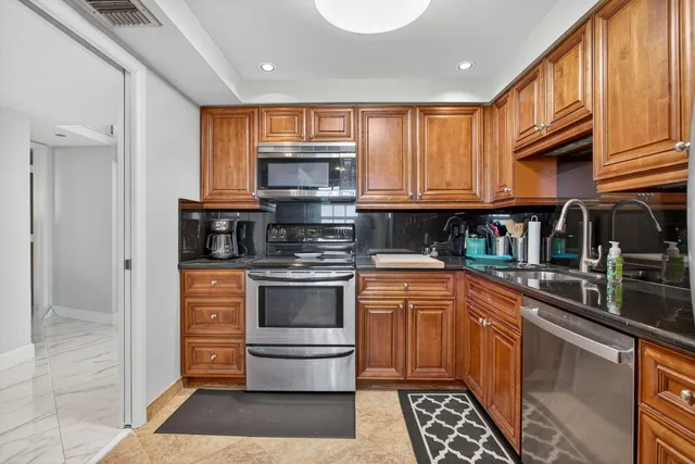 a kitchen with stainless steel appliances granite countertop a stove a sink and a microwave