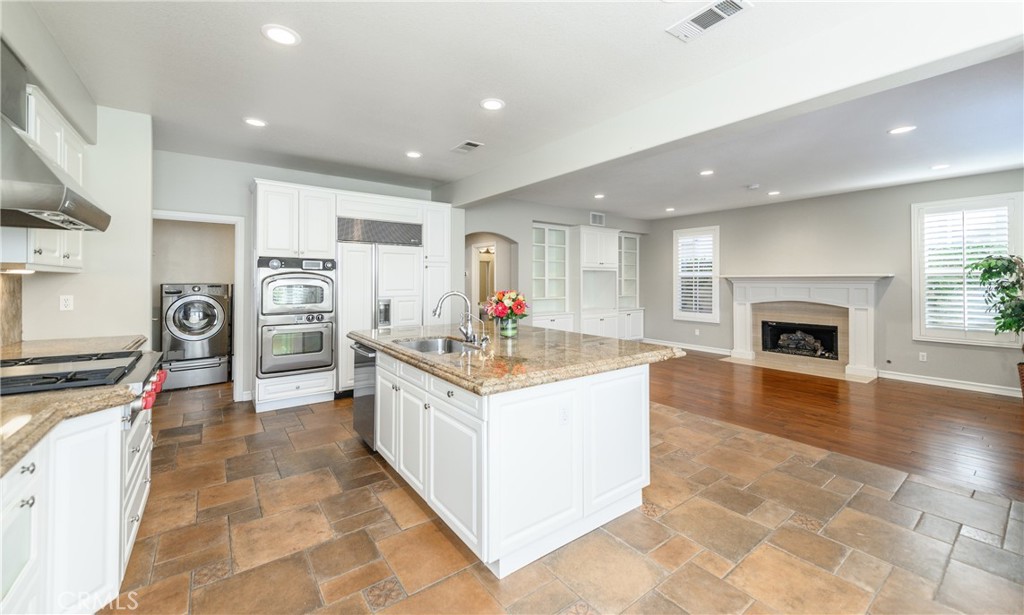 2 Bayleaf Lane Irvine, CA 92620 - Photo 22 of 40 a large kitchen with stainless steel appliances granite countertop a stove top oven a sink dishwasher and a fireplace with wooden floor