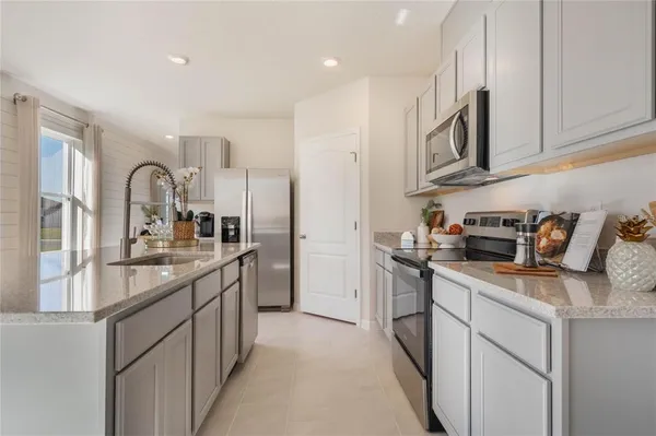 a kitchen with stainless steel appliances granite countertop a stove top oven a sink a refrigerator and white cabinets
