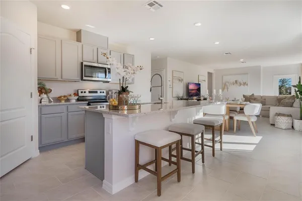 a living room with stainless steel appliances furniture a rug and a kitchen view