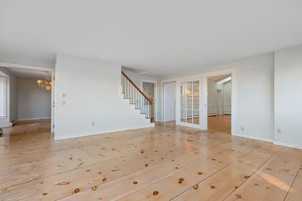an empty room with wooden floor fireplace and windows