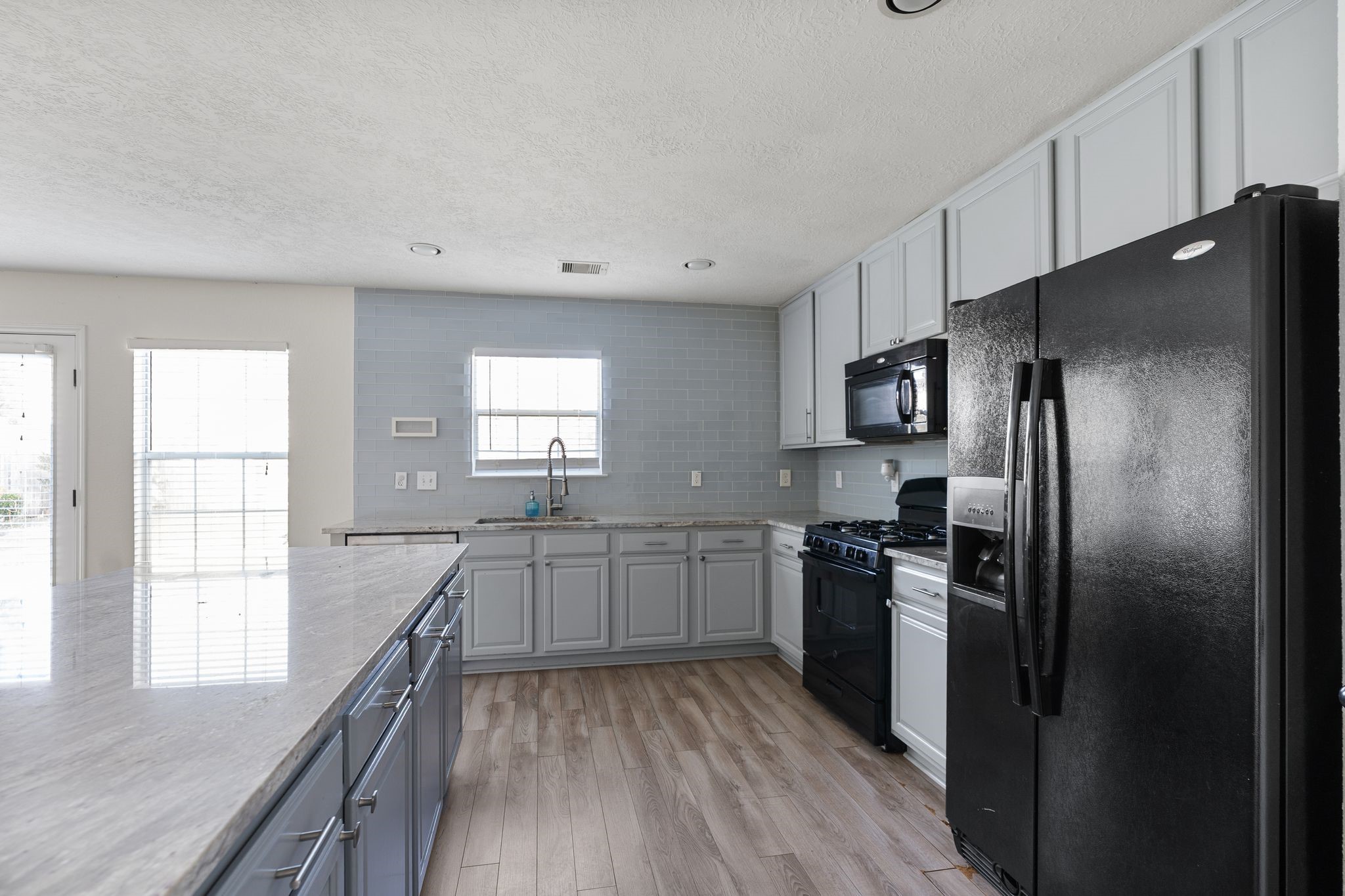 18102 Clayton Bluff Lane Cypress, TX 77433 - Photo 13 of 30 a kitchen with granite countertop stainless steel appliances a refrigerator cabinets and wooden floor