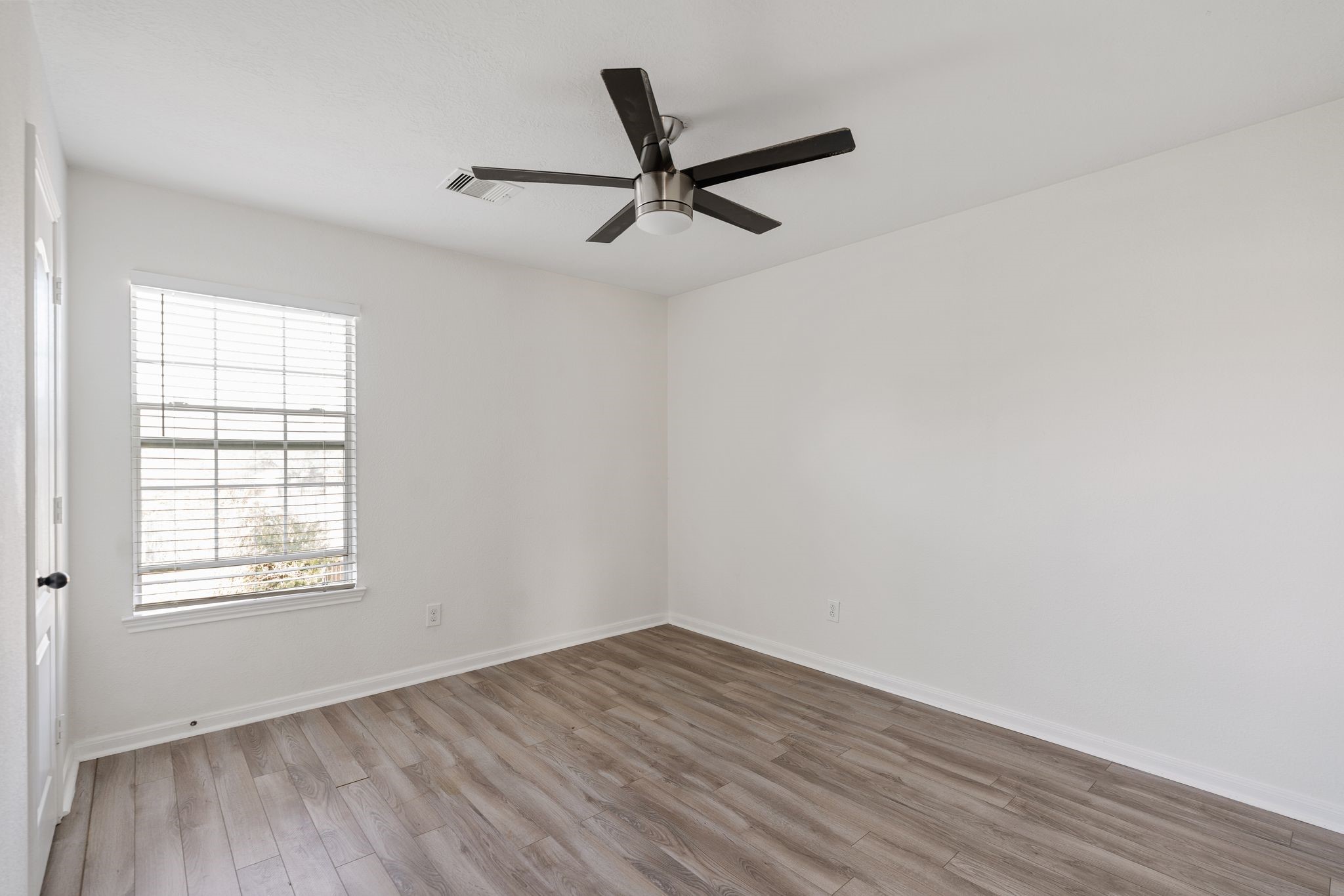 18102 Clayton Bluff Lane Cypress, TX 77433 - Photo 24 of 30 an empty room with wooden floor a ceiling fan and windows