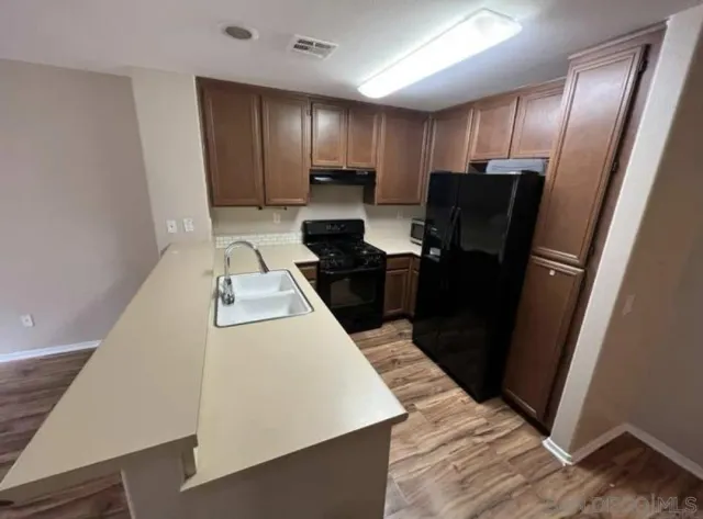 a kitchen with a refrigerator and wooden floor