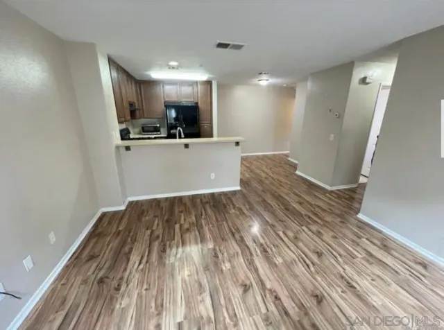 a view of kitchen and empty room with wooden floor