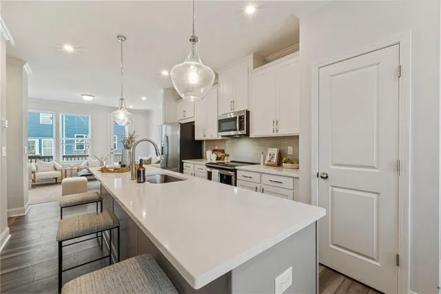 a large white kitchen with lots of counter space dining table and stainless steel appliances