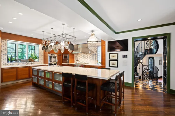 a kitchen with a stove center island wooden floor and living room view
