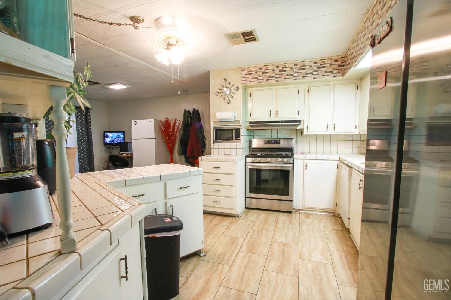 Undisclosed Address Bakersfield, CA 93304 - Photo 12 of 27 a kitchen with a refrigerator a stove top oven and cabinets