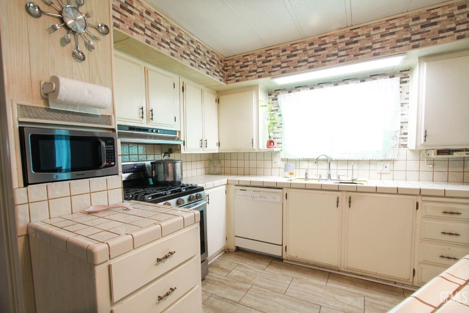 Undisclosed Address Bakersfield, CA 93304 - Photo 10 of 27 a kitchen with a stove a sink and a microwave