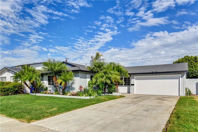 a view of a house with a yard plants and a large tree
