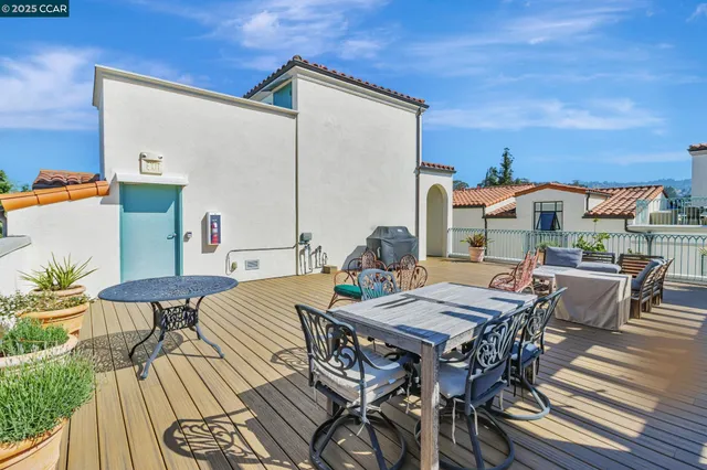 a view of a roof deck with table and chairs couches with wooden floor and fence