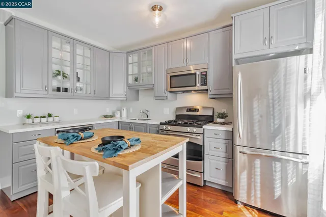 a kitchen with stainless steel appliances a stove a refrigerator a sink a stove with white cabinets