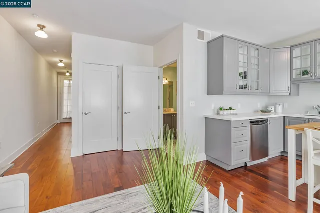 a kitchen with granite countertop a refrigerator a stove a sink and white cabinets with wooden floor