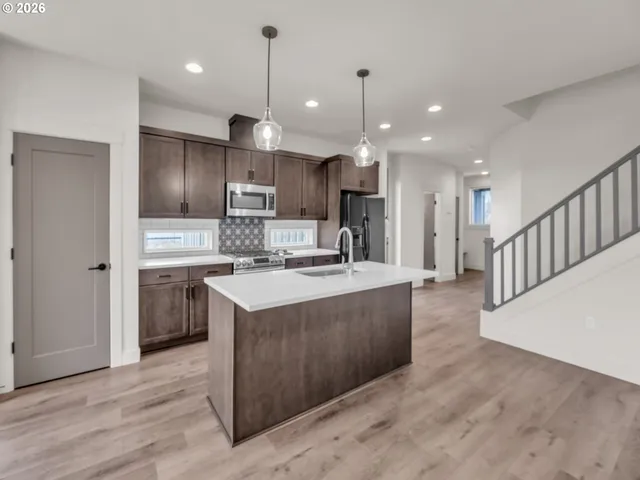 a large kitchen with stainless steel appliances kitchen island granite countertop a sink a stove and a refrigerator