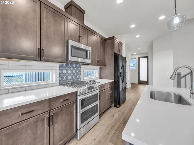 a kitchen with stainless steel appliances granite countertop a sink stove and refrigerator