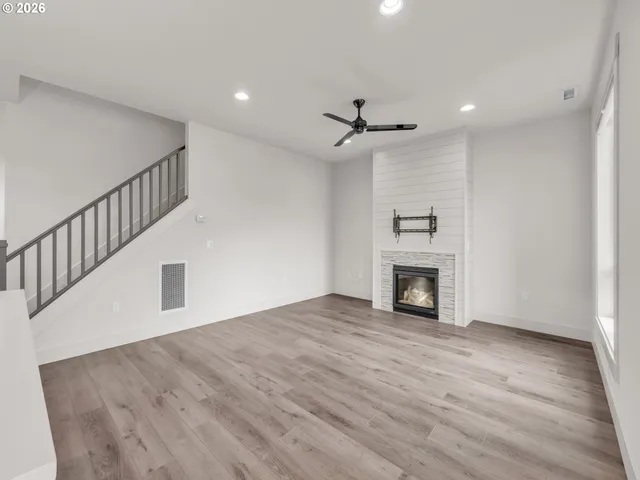 a view of an empty room with wooden floor fireplace and a window