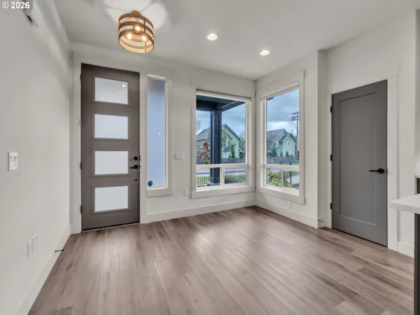 a view of an empty room with a window and wooden floor
